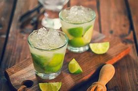 Caipirinha tradicional brasileira, feita com limão, açúcar e cachaça, servida com gelo picado em um copo de vidro.